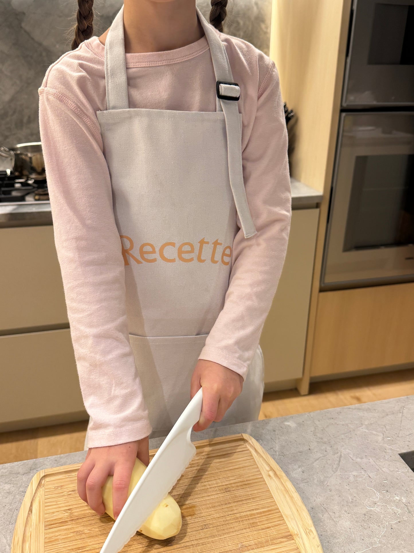 Child wearing a Recette apron cooking