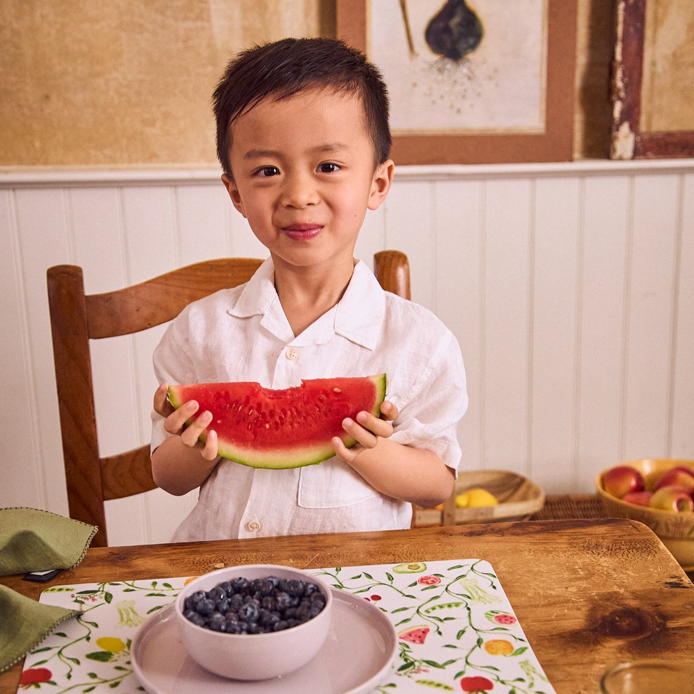 smiling boy eating fruit off pastel dishware