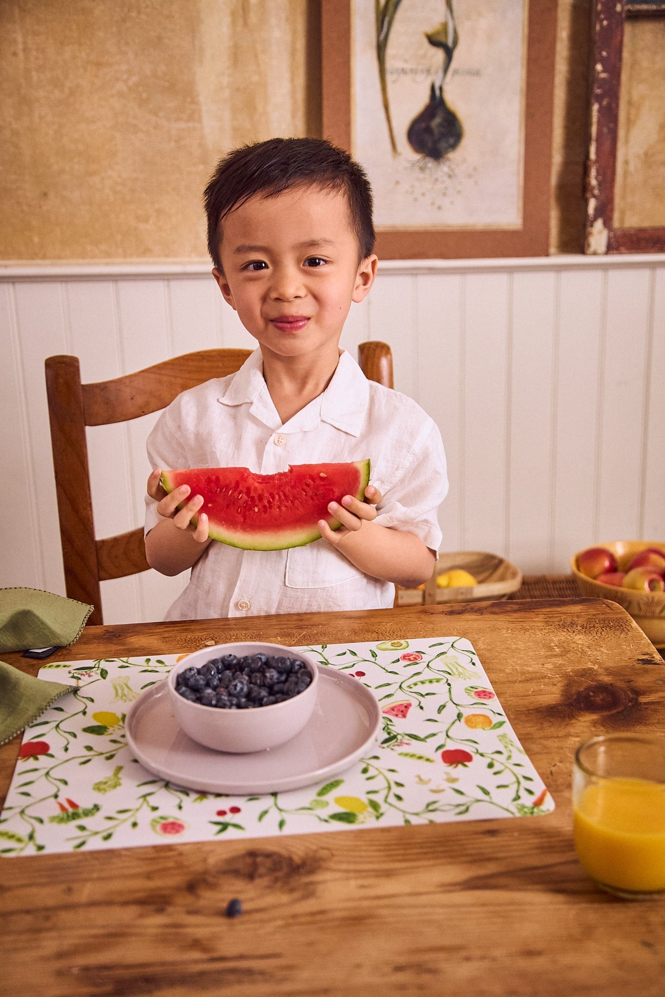 smiling boy eating fruit off of pastel plate and bowl