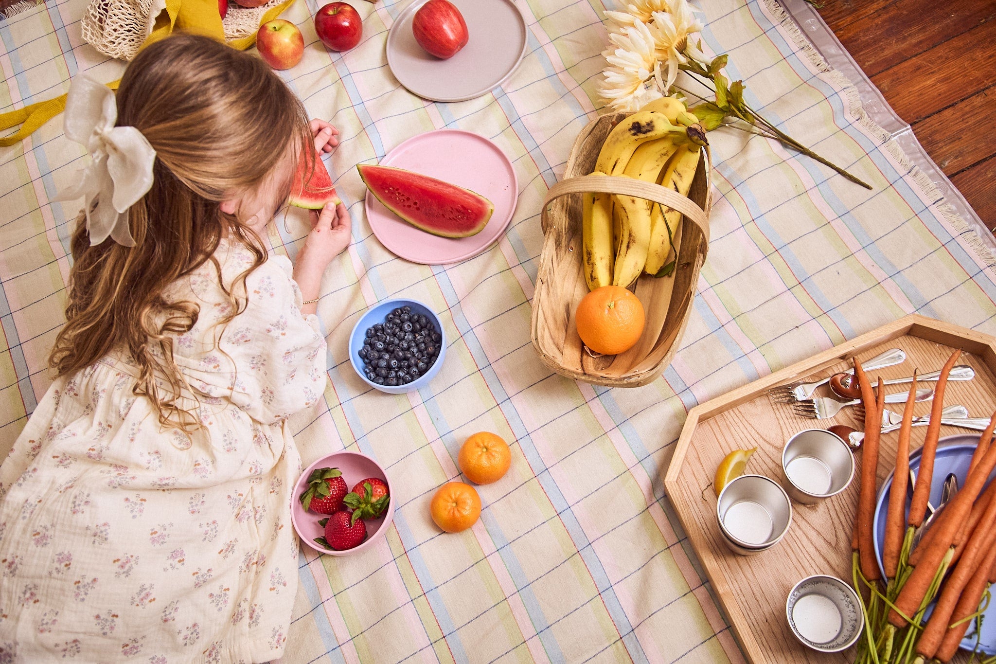 Little girl on a picnic blanket eating watermelon and fruit off recette plates