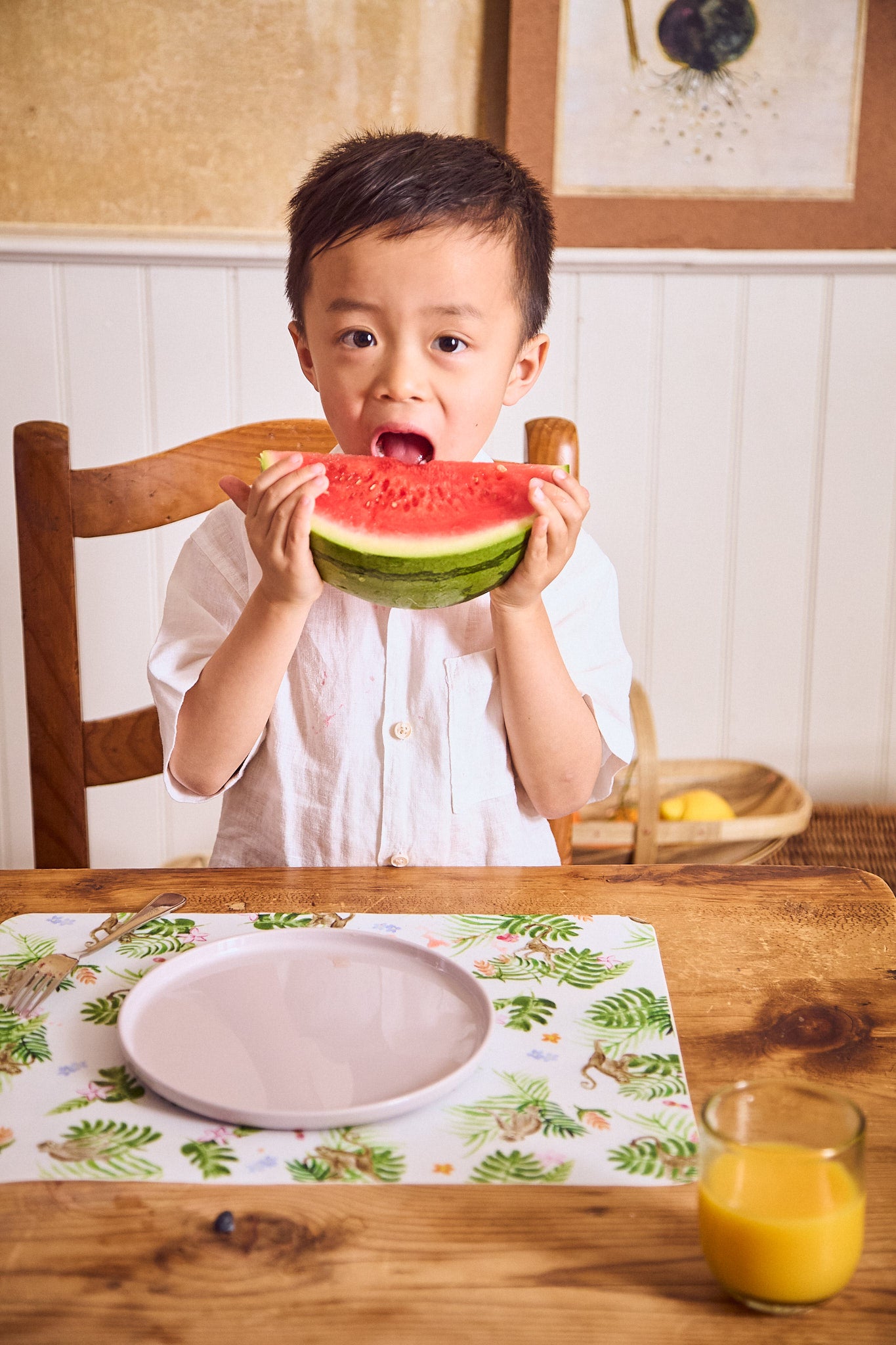 Kid eating a big slice of watermelon off a neutral recette plate