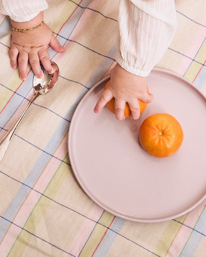 Baby grabbing a fresh clementine from a pastel recette plate