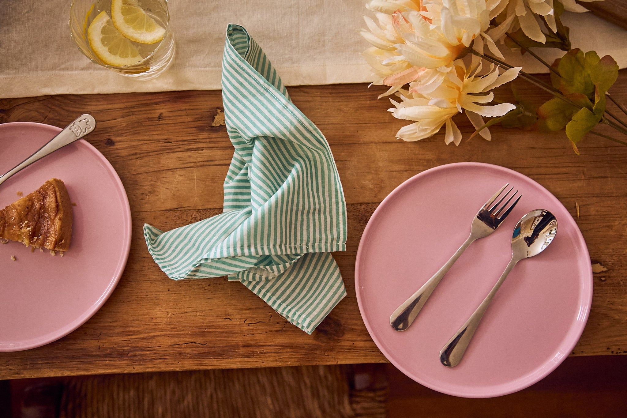Overhead shot of a warm wood table with non-toxic pink dinnerware and silverware